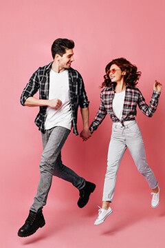 Couple jumping in front of a pink background